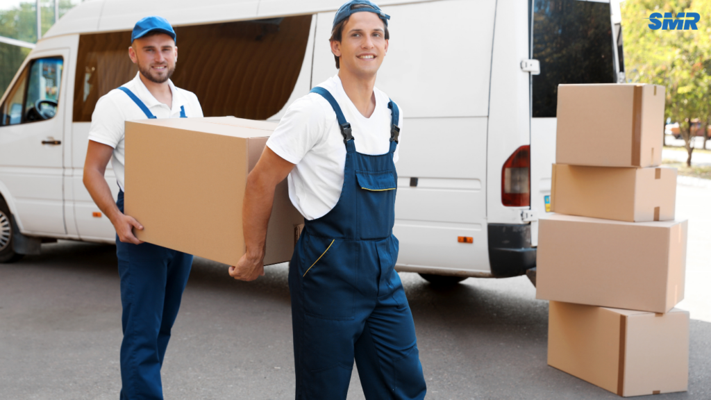 Movers handling office desks, computers, and boxes
